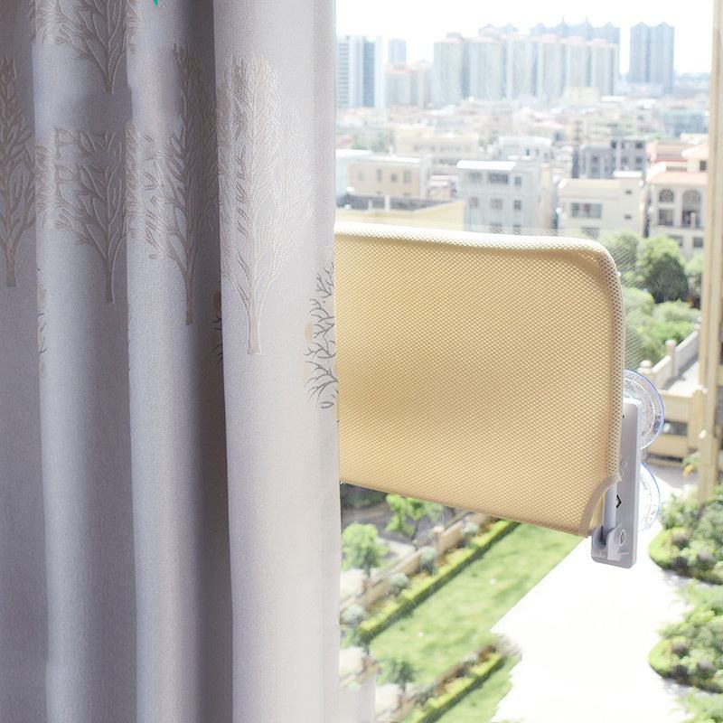 Beige plush cat window hammock mounted on glass with strong suction cups, showing city view outside window.