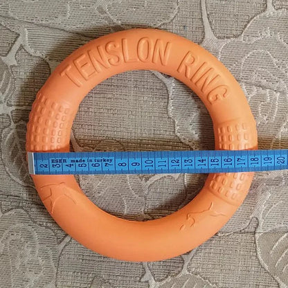 Orange EVA Pull Play Ring for dogs with a measuring tape showing size on a textured surface